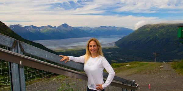 Woman standing at the peak of Mt. Alyeska in the summer overlooking the inlet
