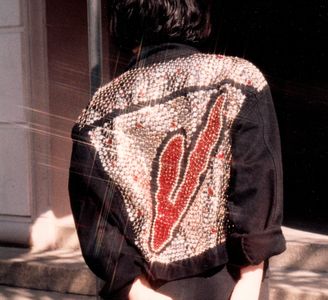 Girl wearing a black denim Levi's jacked studded with silver metal and red crystals in a V pattern