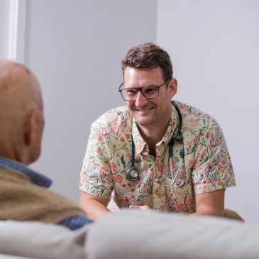 Doctor smiling while talking to an elderly patient.