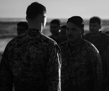 Military personnel engaged in serious conversation at sunset.