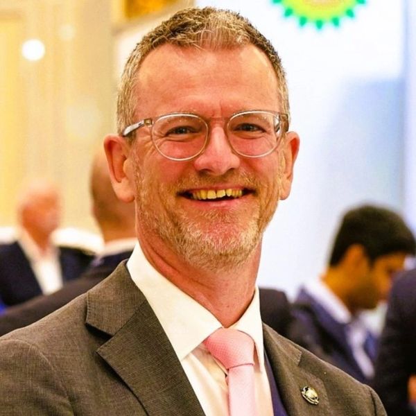 Smiling man in glasses and suit at a formal event.