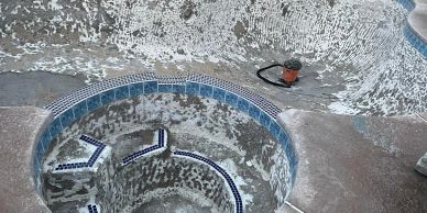 Empty, deteriorating swimming pool with worn-out tiles.