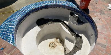 Damaged hot tub with broken sections and missing tiles.