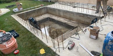Concrete pool under construction with metal rods and tools around.