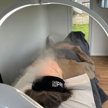 Person wearing a medicID eye mask receives facial steam treatment indoors.