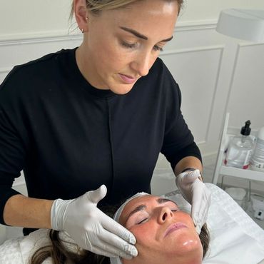 A woman receives a facial treatment from a professional in gloves.
