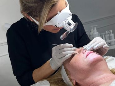 A beautician performs a facial treatment on a client in a spa setting.