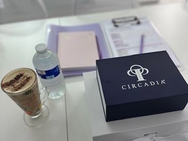A table with a coffee, water bottle, and Circadia gift boxes in a bright room.