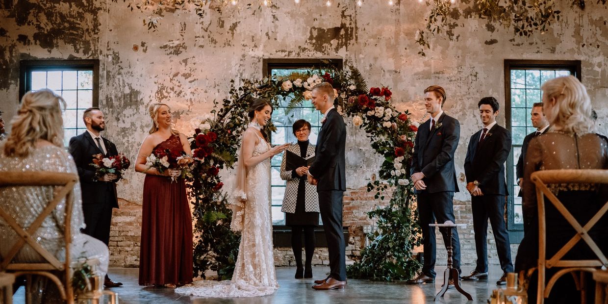 Ontario wedding Officiant marrying a couple at an Ontario wedding venue, floral arch in view.