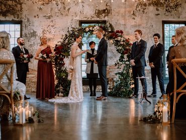 Wedding ceremony with an Ontario Wedding Officiant, a couple and wedding party in front of flowers.