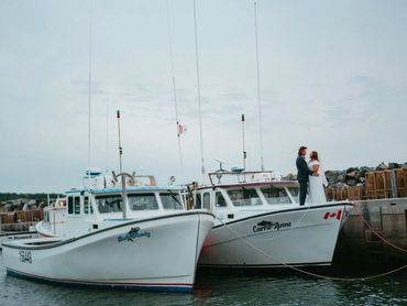 Nova Scotia elopement with a bride and groom standing on the front bow of a lobster boat.