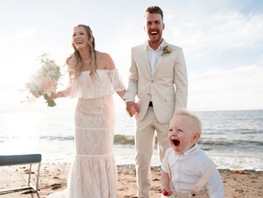 Nova Scotia elopement on a beach showing smiling bride and groom with a small child.