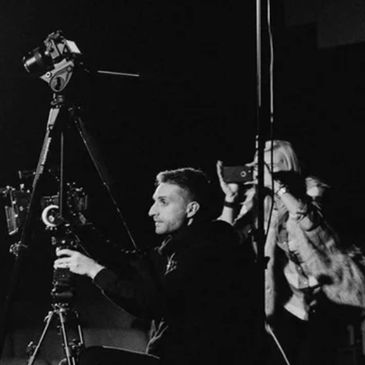 Man setting up video cameras while a woman films with a smartphone.