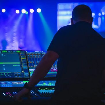 Person operating a sound or lighting control board at an event.