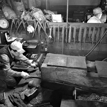 Two workers operating tools in a workshop.