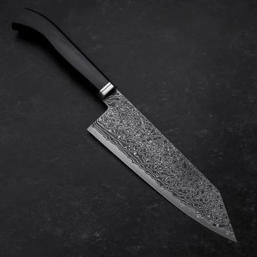 Intricately patterned kitchen knife on dark surface.