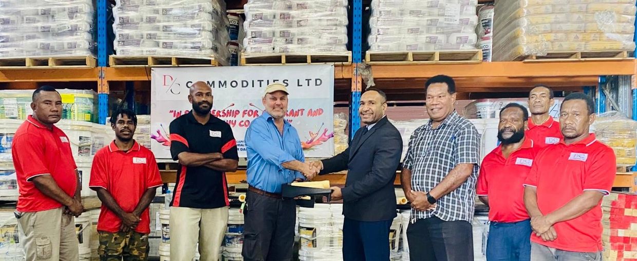 Group of men shaking hands in a warehouse setting.