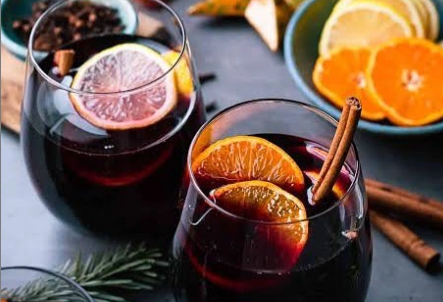 This image shows warm mulled wine with a cinnamon stick and fresh citrus.