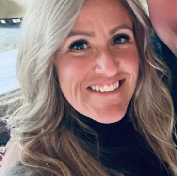 Woman with long blonde hair smiling at camera.