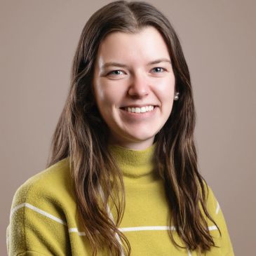 Woman with long brown hair smiling at camera