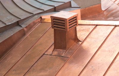 Close-up of a copper roof vent on a metal roof.