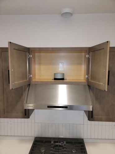 Open kitchen cabinet above a stainless steel dishwasher.