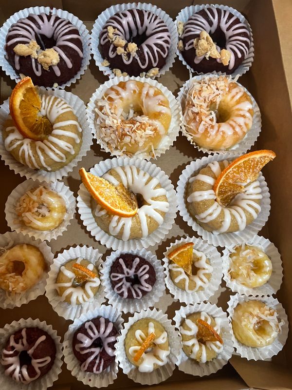 Assorted mini donuts with various toppings in a box.