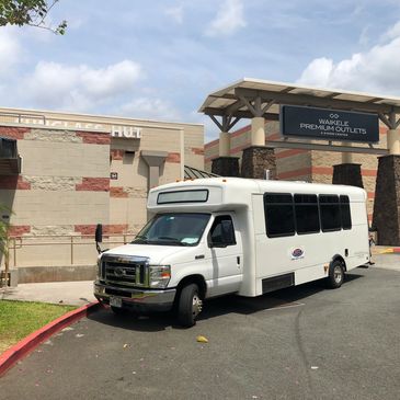 A white mini bus parked outside a mall