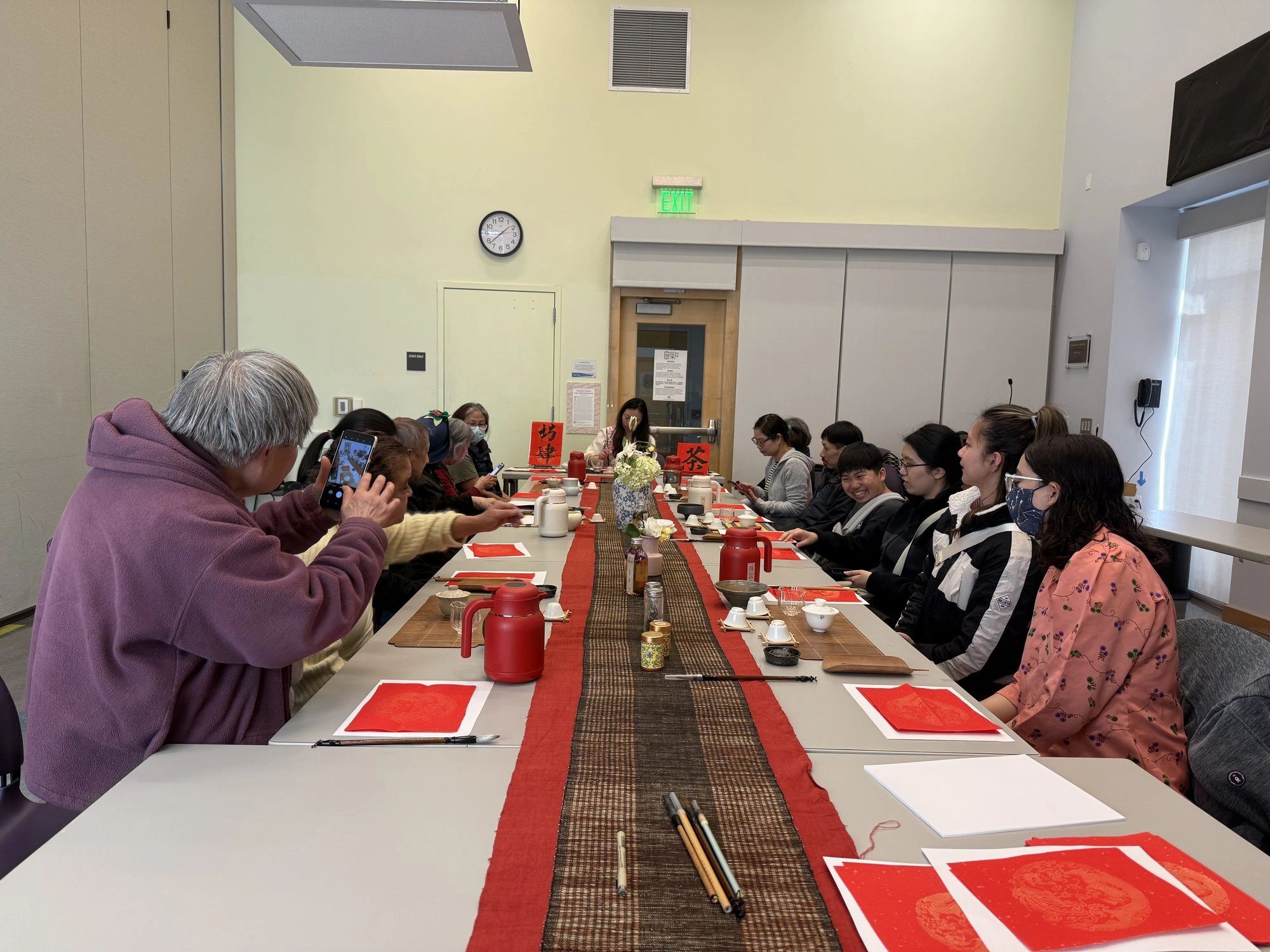 Participants practicing calligraphy at long tables during a public library cultural program