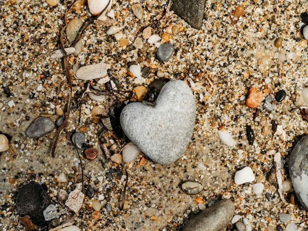 a heart-shaped grey stone on a gravel sand surface
