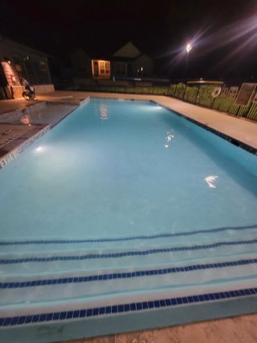 Nighttime view of a lit swimming pool with steps in the foreground.