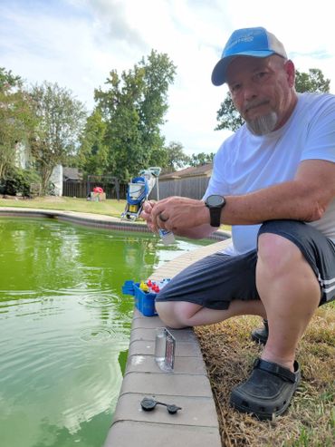 Man testing pool water with a kit by a greenish pool.