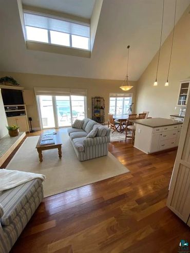 Bright open living room with striped sofas and wooden floors.