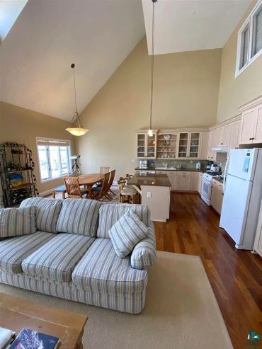 Cozy open-plan living room and kitchen with vaulted ceiling and wooden floors.
