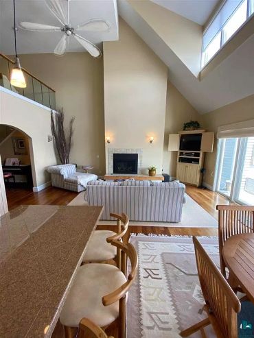 Bright living room with high ceilings, fireplace, and striped furniture.