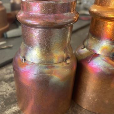 Close-up of two metallic cylindrical objects with a colorful patina.