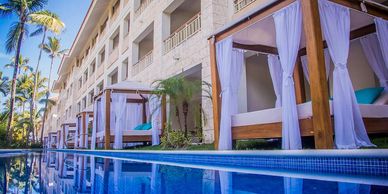 Luxury poolside cabanas with white curtains at a tropical resort.