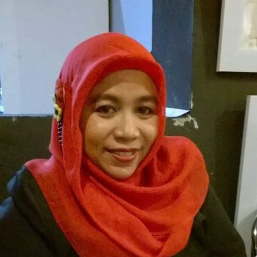 Smiling woman wearing a red hijab indoors.