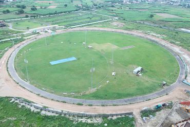 Aerial view of a large, empty cricket stadium surrounded by greenery.
