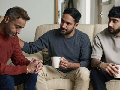 Three men having a serious conversation on a couch.