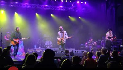 Band performing live on stage with colorful lights.