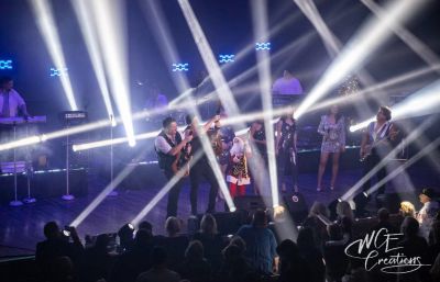 Band performing live on stage with bright lights and audience.