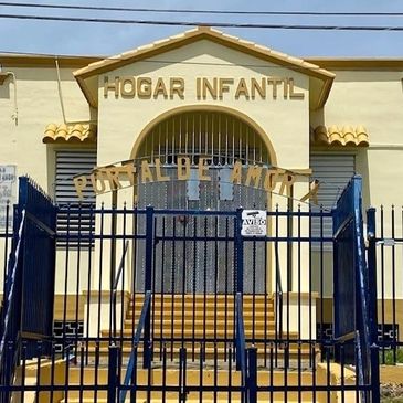 Entrada de un hogar infantil con rejas y cartel.