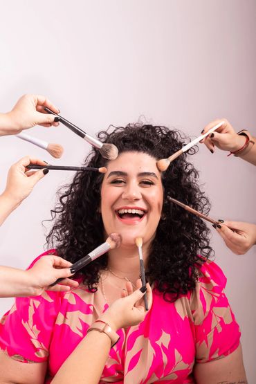 mulher sorrindo com várias mãos segurando pincéis em direção a ela