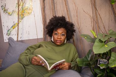 mulher negra escorada em poltrona segurando um livro