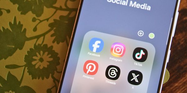 Smartphone screen showing popular social media app icons in a folder to show their array of content creation platforms.