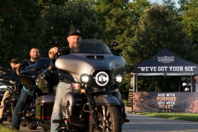 Bikers riding near a tent with motivational messages.