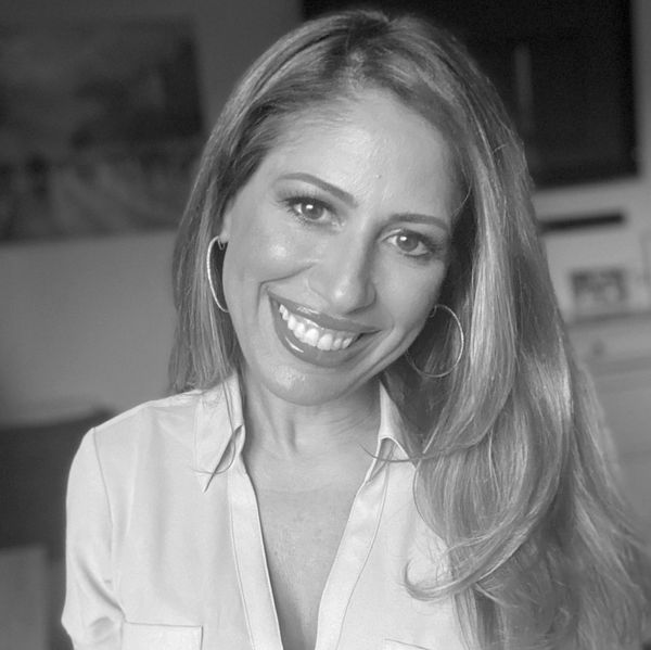 Smiling woman with long hair and hoop earrings.