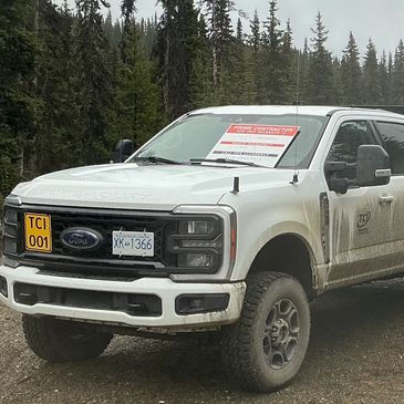 White Ford pickup truck parked on a dirt road with a for sale sign on the windshield.