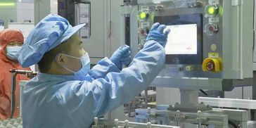 A worker in protective gear operating industrial machinery in a cleanroom environment.